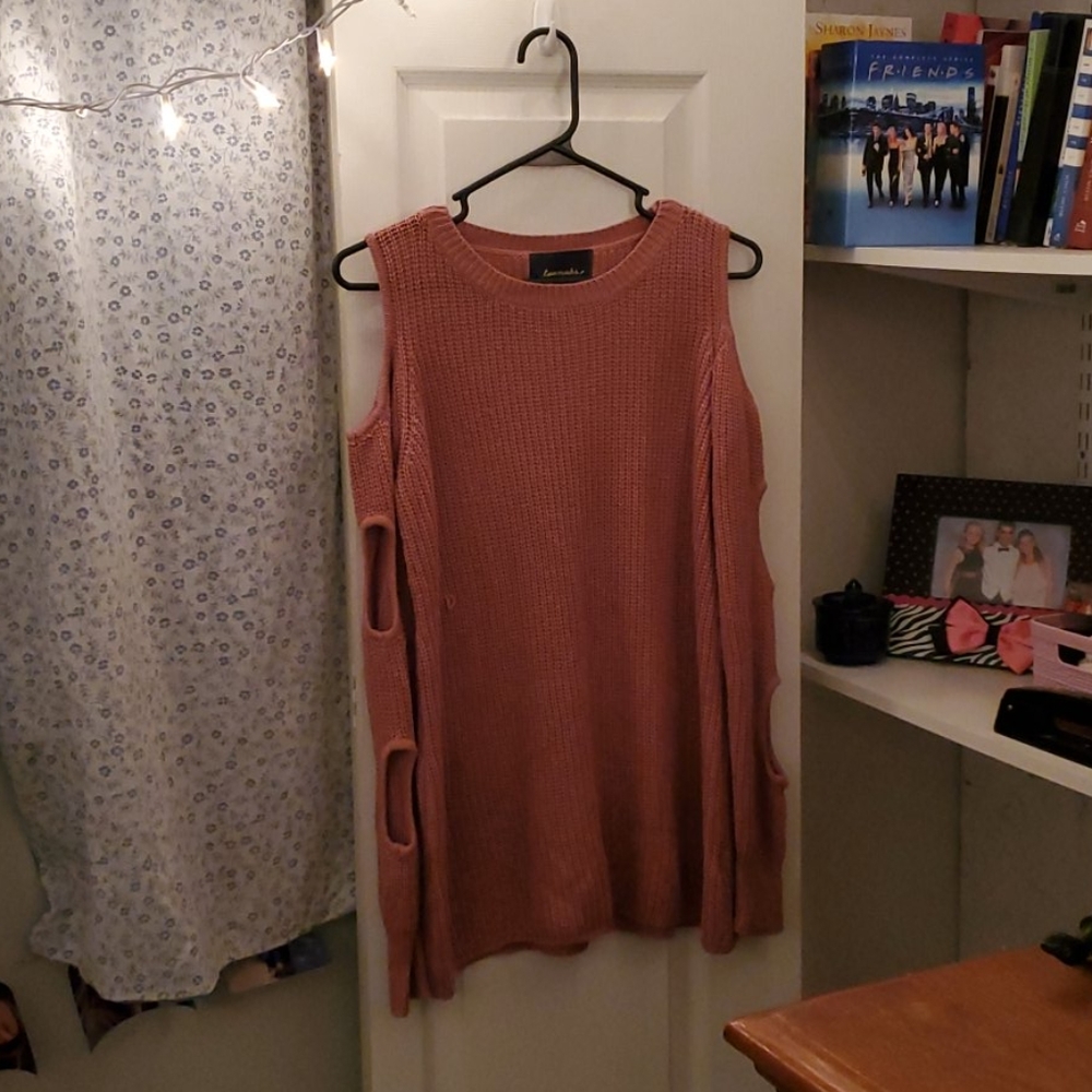 A rose-pink knit sweater with holes in the sleeves